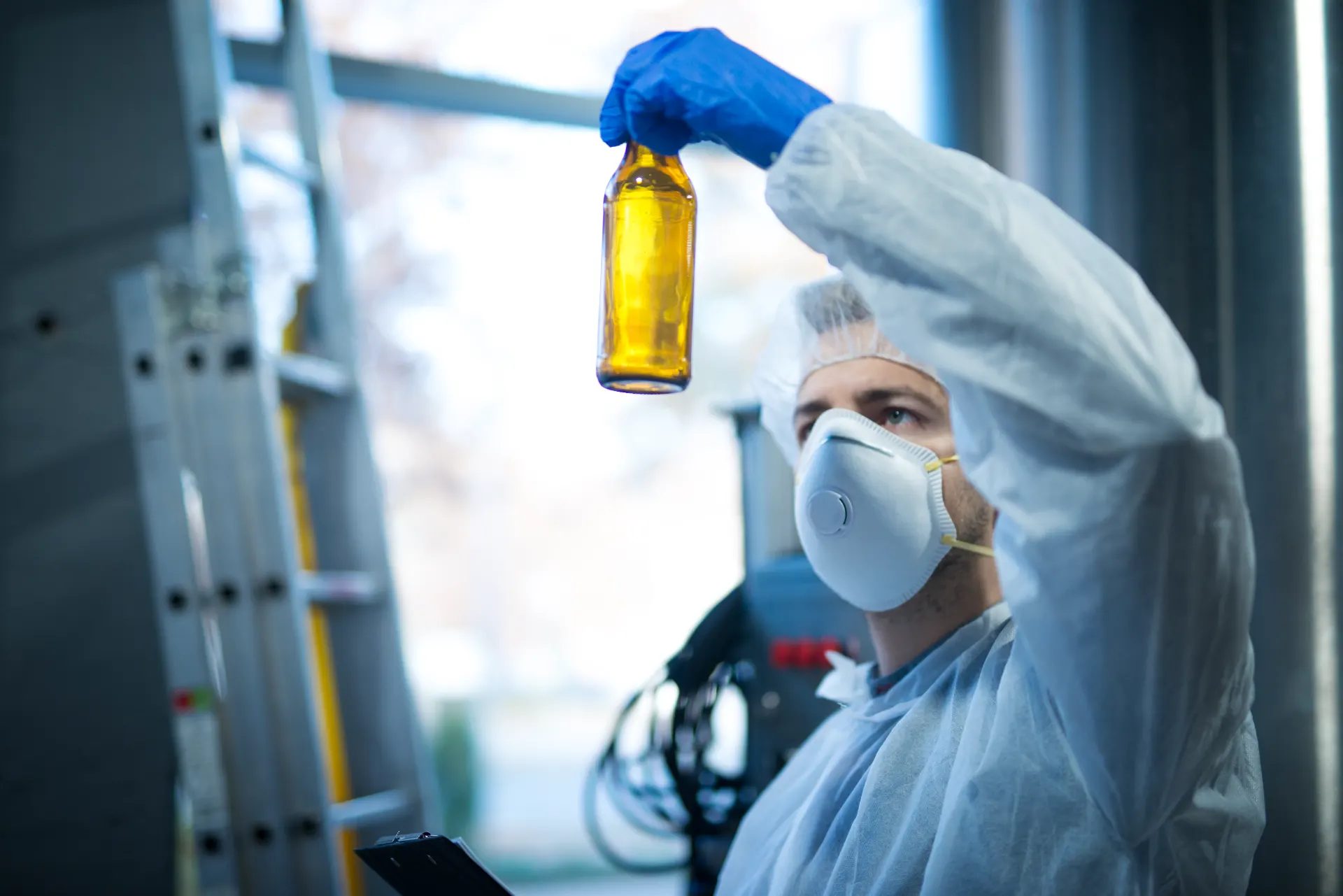 Pesquisa em laboratório: cientista com máscara e luvas analisa frasco com líquido amarelo durante experimento, destacando o conceito de água no óleo em testes de mistura e contaminação.