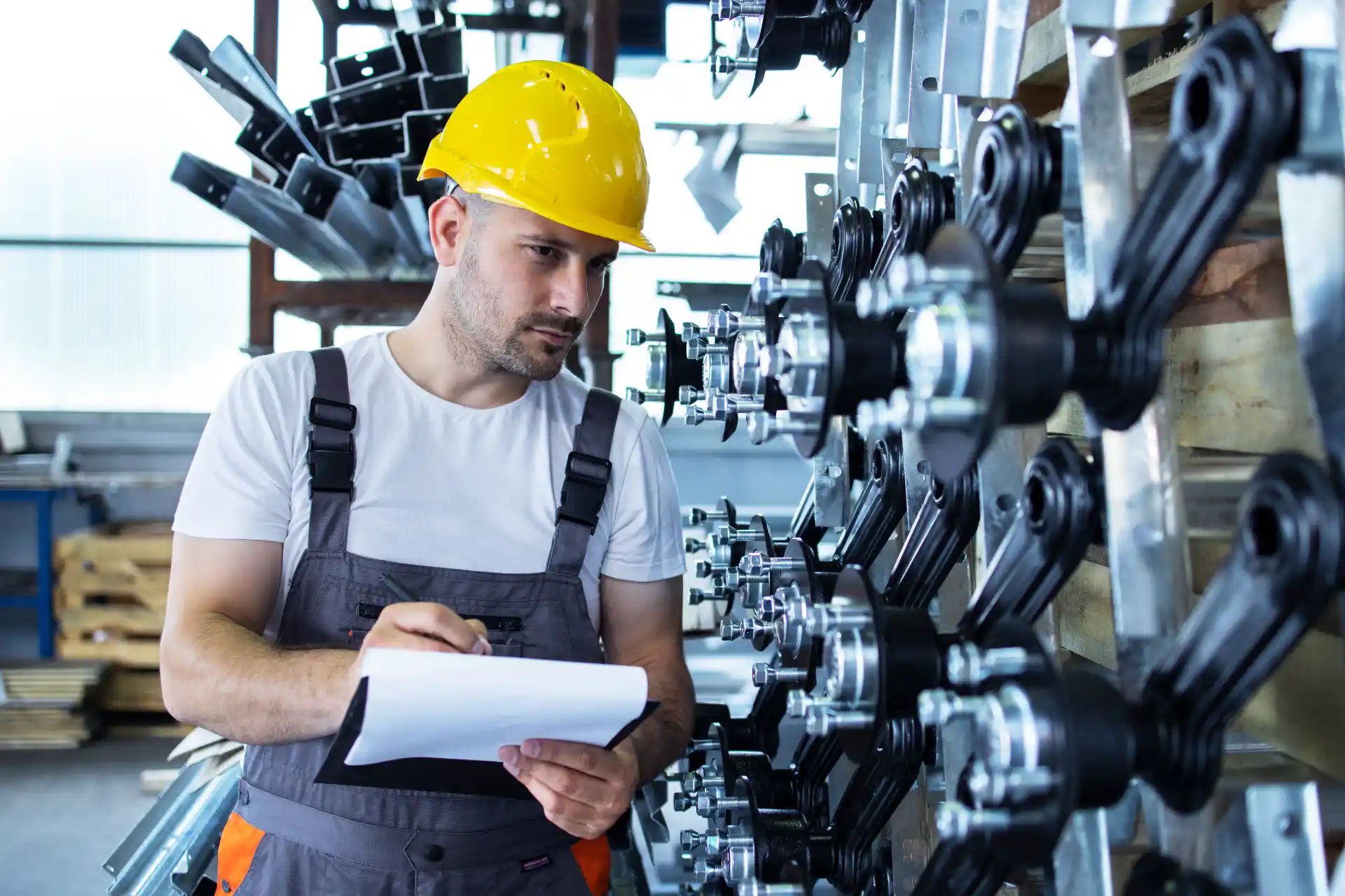 Trabalhador industrial com capacete e uniforme em ambiente de usinagem, inspecionando um conjunto de máquinas e componentes mecânicos para controle de contaminação no óleo durante a operação.